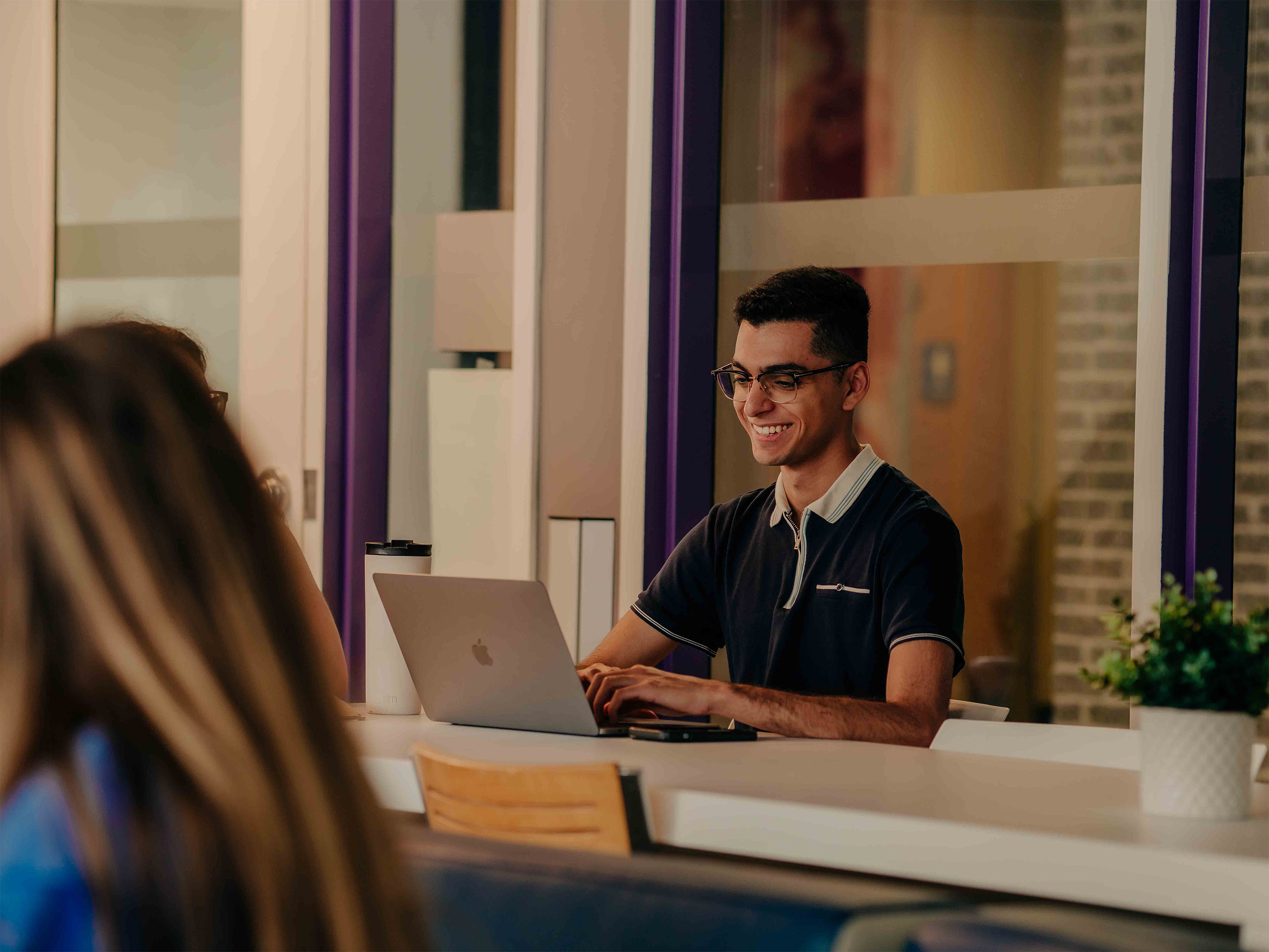 Student sitting in the faculty of arts lounge on their laptop.